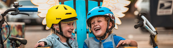 Children in snow gear and helmets at ski area.