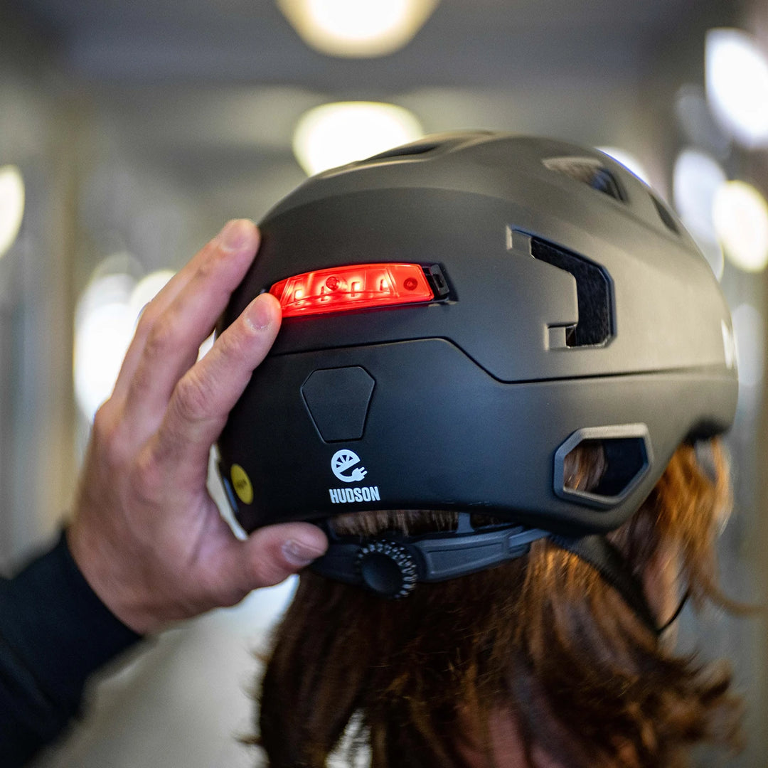 Person turning on bern click mount light installed on Hudson e-bike helmet.