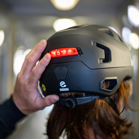 Person turning on bern click mount light installed on Hudson e-bike helmet.