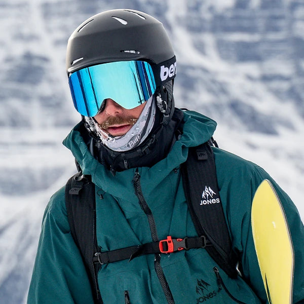 Man wearing Bern Hendrix Winter Helmet with B-1 Goggles carrying snowboard