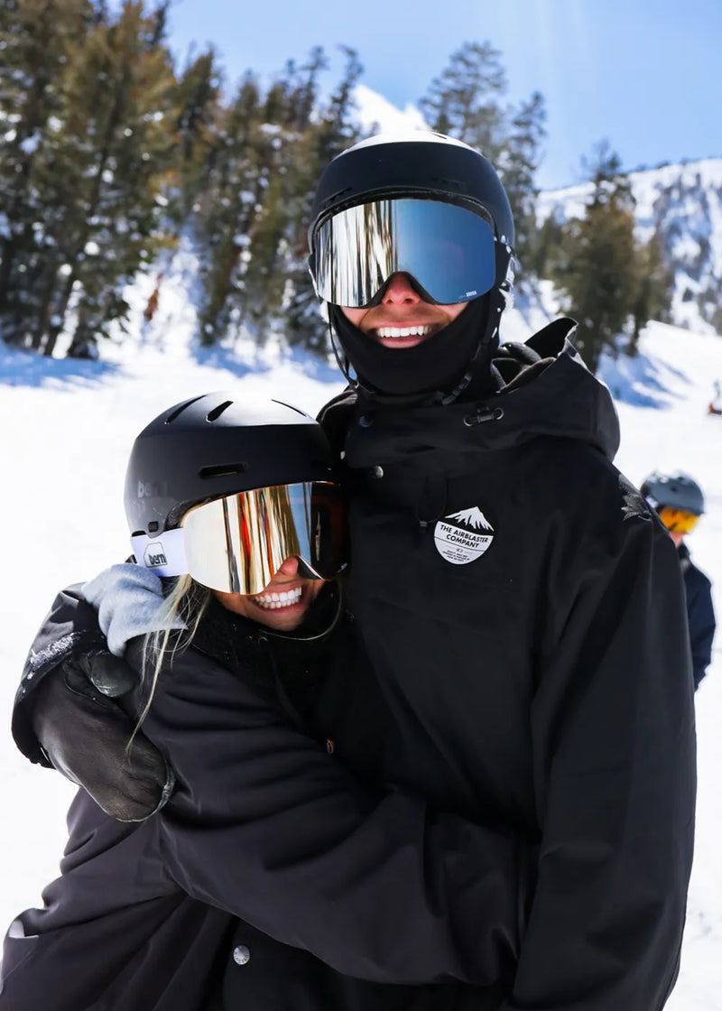 Couple skiing at a resort wearing the bern b-1 zeiss goggles
